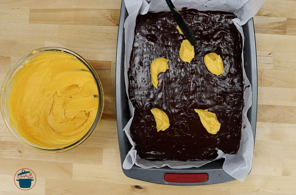 Gradually pour the cream cheese pumpkin filling over the brownie batter. Gradually-pour-the-cream-cheese-pumpkin-filling-over-the-brownie-mixture