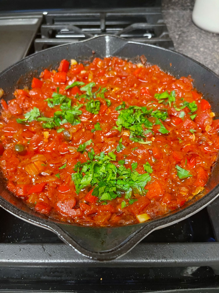 Once it starts boiling, reduce the heat to low and let it simmer for around 20 minutes, or until the mixture is slightly reduced. Add parsley and stir it in. Stir in the tomatoes, using a wooden spoon to break them into small chunks. Place the mixture on medium heat and wait until it boils.