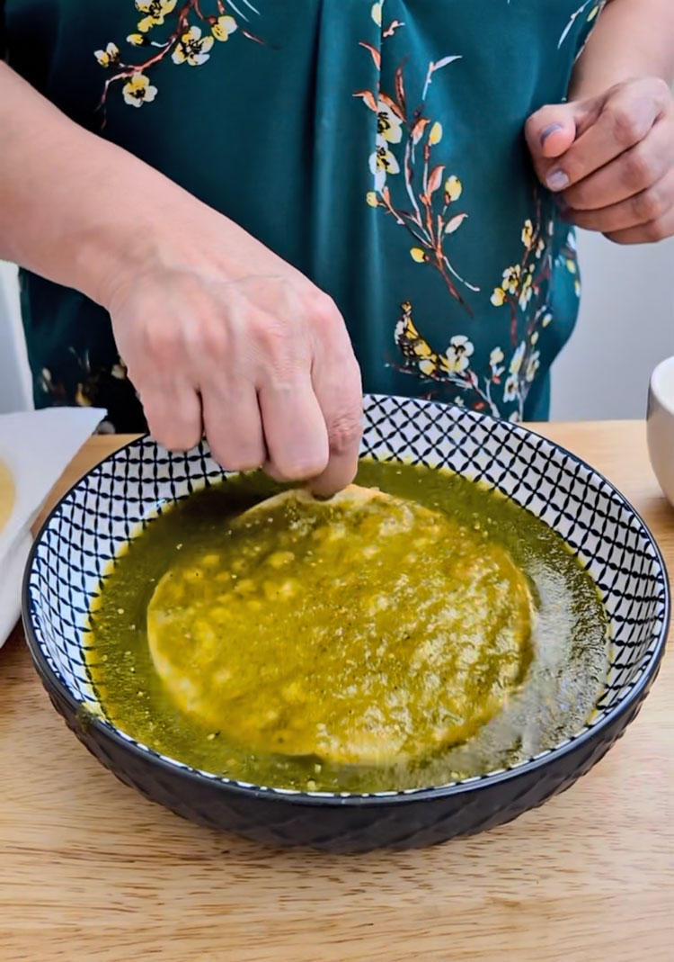 Dip each tortilla into the green enchilada sauce to coat both sides. Dip-each-tortilla-into-the-green-enchilada-sauce-to-coat-both-sides
