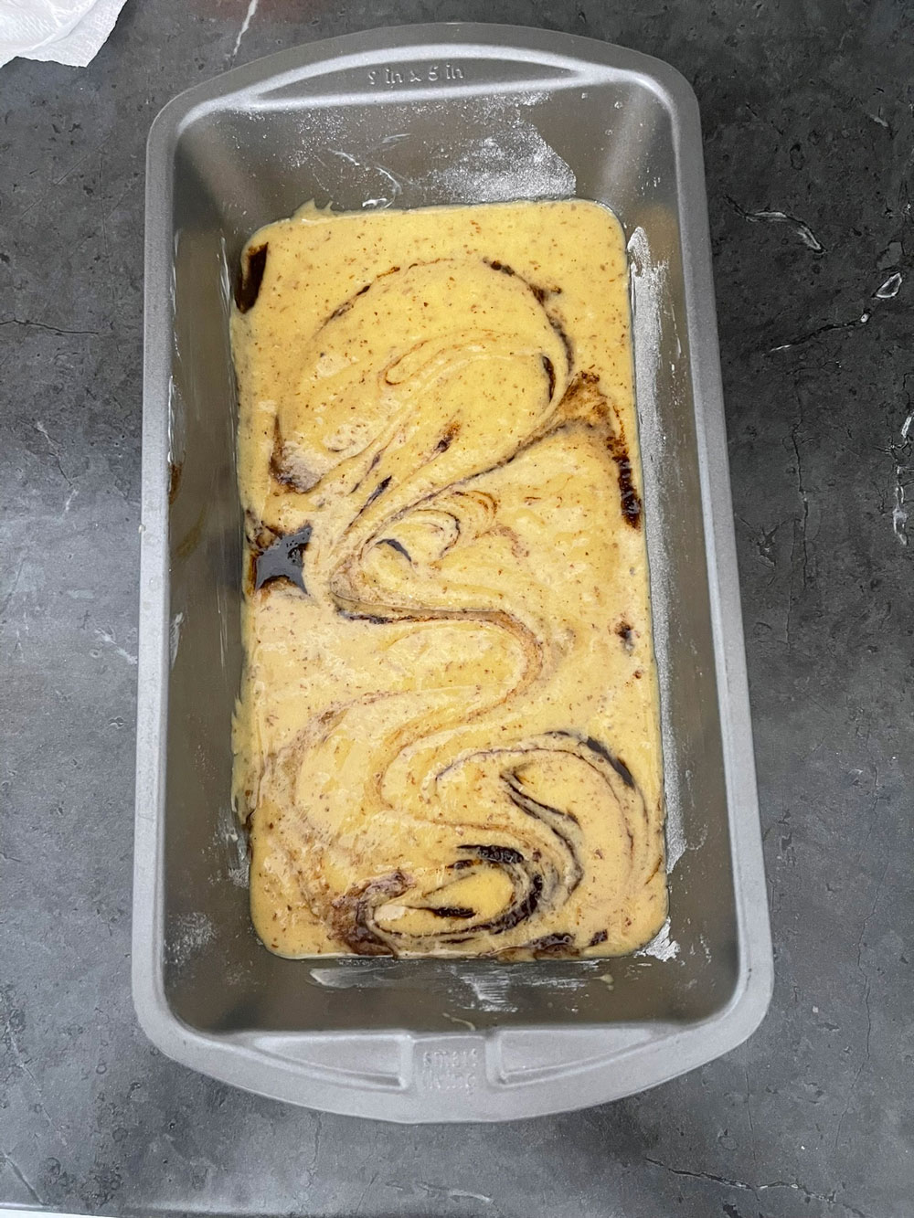 Pour half of the cake batter into your prepared baking pan Add the cinnamon mixture on top, then pour the remaining batter over it. Use a table knife or toothpick to swirl it into the batter. I topped it with some chopped pecans; however, this is optional. CINNAMON-SWIRL-CAKE