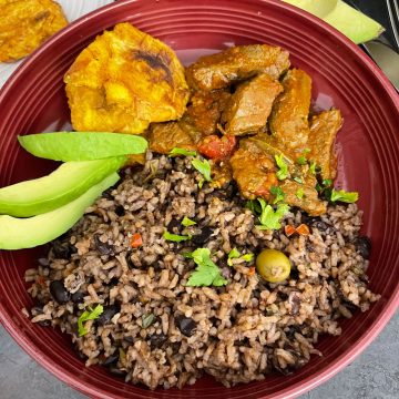 Dominican moro de habichuelas negras ( rice and beans) served on a plate with meat and avocado